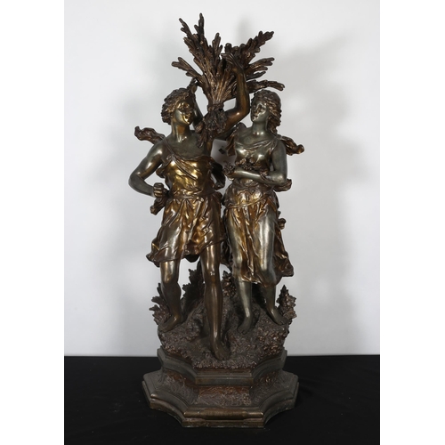 409 - A SPELTER AND BRONZED GROUP modelled as a female and a companion each shown standing holding a sheaf... 