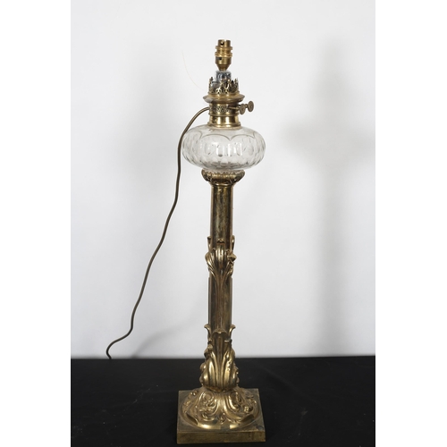 410 - A BRASS ART NOUVEAU OIL LAMP now converted the faceted bulbous reservoir above a foliate embossed co... 