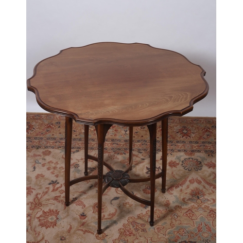 456 - AN ARTS AND CRAFTS CARVED MAHOGANY OCCASIONAL TABLE the shaped top raised on carved and moulded legs... 