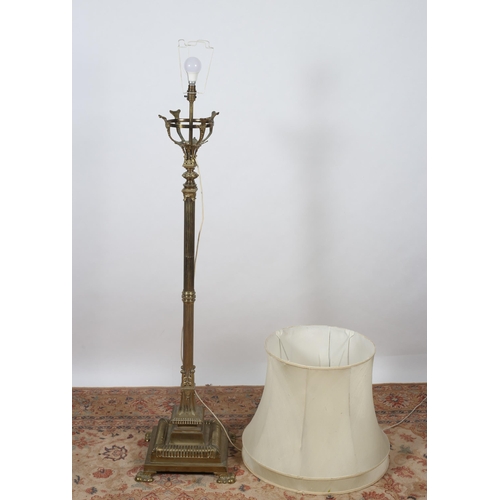 470 - A 19TH CENTURY BRASS STANDARD LAMP the reeded column above a lobed platform on claw feet with shade ... 