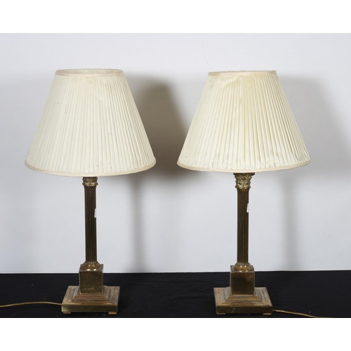 478 - A PAIR OF BRASS CORINTHIAN COLUMN TABLE LAMPS each with a reeded column raised on a square stepped b... 