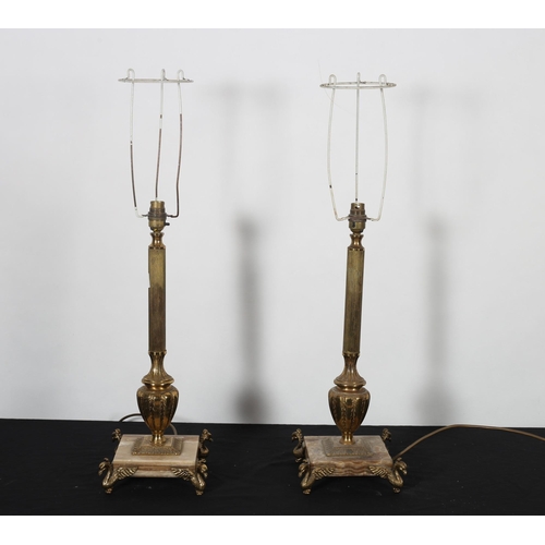 479 - A PAIR OF GILT BRASS AND ONYX TABLE LAMPS each with a reeded urn column above a square platform on f... 