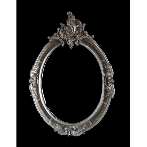 488 - A CONTINENTAL SILVER FRAMED MIRROR the oval bevelled glass plate within a moulded frame with pierced... 