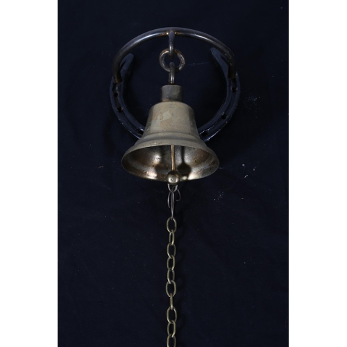 498 - A BRASS HANGING BELL raised on a horseshoe back plate 20cm(h) 16cm(w)