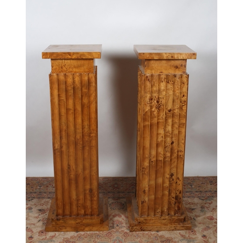 76 - A PAIR OF ART DECO DESIGN WALNUT PEDESTALS each of square outline the shaped tops above a fluted col... 