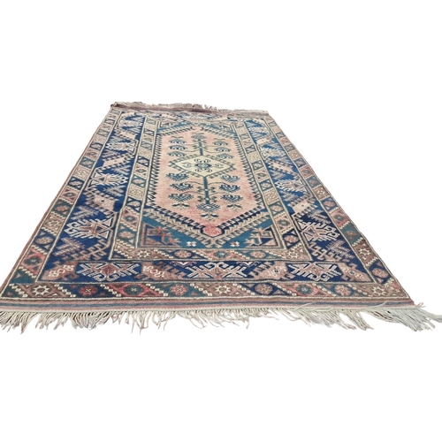 803 - AN ORIENTAL WOOL RUG the light pink and indigo ground with central panel filled with serrated panels... 