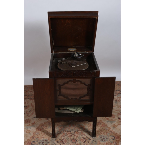 213 - A VINTAGE OAK GRAMOPHONE the hinged lid containing a turntable inscribed 'Harmonophone' above a pair... 