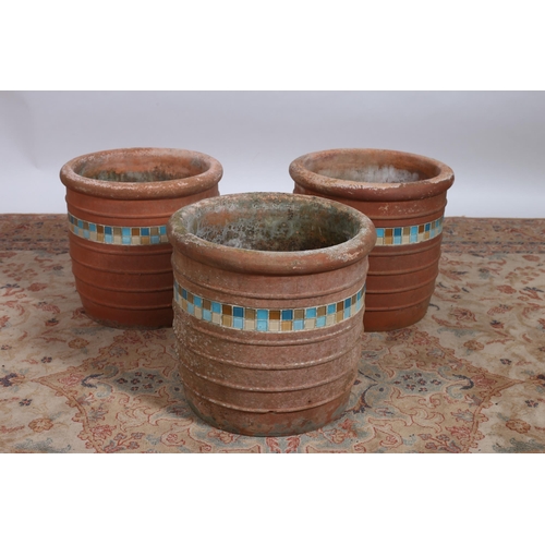 219 - A SET OF THREE TERRACOTTA PLANTERS each of cylindrical tapering form inset with coloured tiles 
Each... 