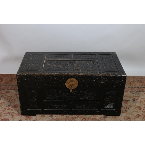 226 - A CHINESE BLACK LACQUERED TRUNK with hinged lid profusely carved overall with figures, flowerheads a... 