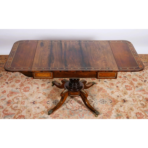 26 - A REGENCY ROSEWOOD AND BRASS INLAID SOFA TABLE the rectangular hinged top with frieze drawer above a... 