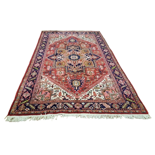 393 - A HERIZ WOOL RUG the beige ground with central panel filled with flowerheads and foliage within a co... 