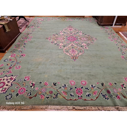 399 - A WOOL RUG the green ground with central floral panel within a conforming border (stained and soiled... 