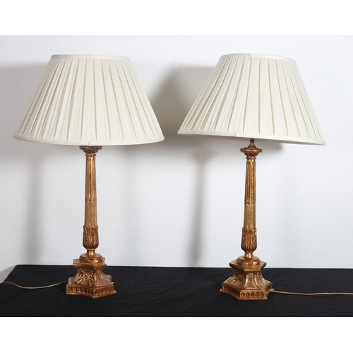 505 - A PAIR OF CONTINENTAL GILT TABLE LAMPS each with a reeded and foliate capped column raised on trifor... 