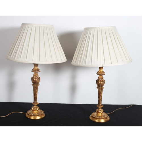 506 - A PAIR OF CONTINENTAL GILT TABLE LAMPS each with a foliate scroll column above a circular spreading ... 