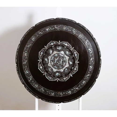 606 - A CHINESE PAPIER MACHE LACQUERED AND MOTHER OF PEARL INLAID PLAQUE of circular outline the shaped fr... 