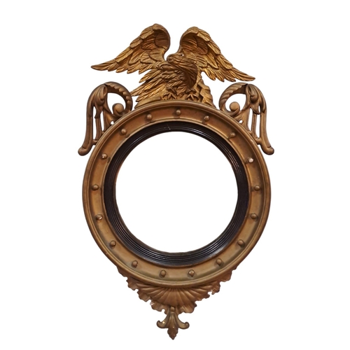 608 - A 19TH CENTURY GILT CONVEX MIRROR the moulded frame with ball decoration surmounted by a winged eagl... 