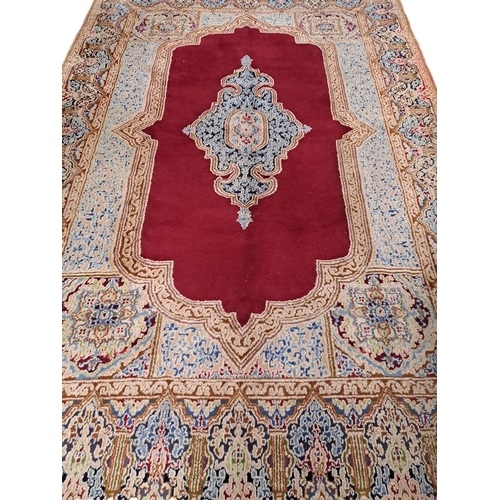 620 - A KESHAN WOOL RUG the wine, light blue and beige ground with central panel filled with floral panel ... 