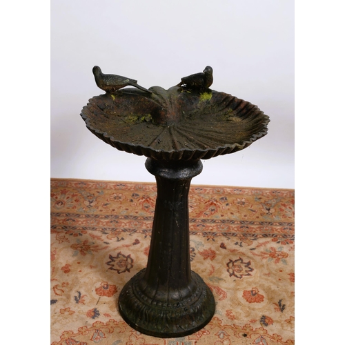 67 - A CAST IRON BIRD BATH the leaf shaped dish surmounted by birds above spreading column on a circular ... 