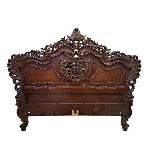 733 - A CONTINENTAL MAHOGANY HEADBOARD of serpentine outline profusely carved overall with pierced C-scrol... 