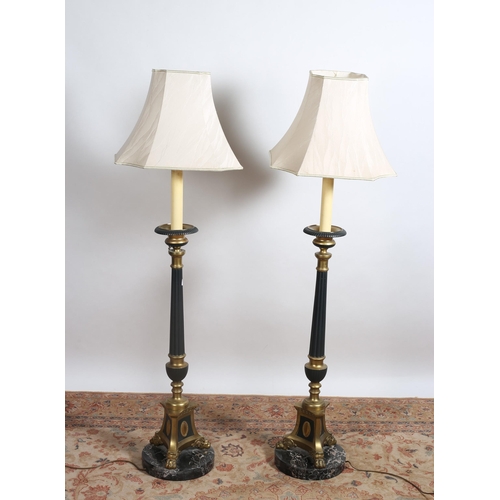 79 - A PAIR OF VINTAGE BRASS AND POLYCHROME LAMPS each with a fluted column on triform base with claw fee... 