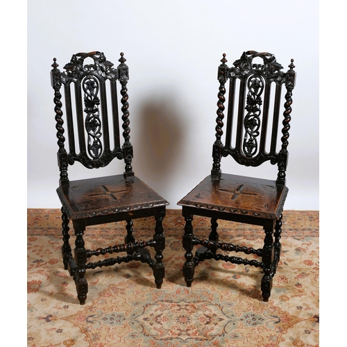 82 - A PAIR OF JACOBEAN STYLE CARVED OAK SIDE CHAIRS each with a pierced foliate carved top rail and spla... 