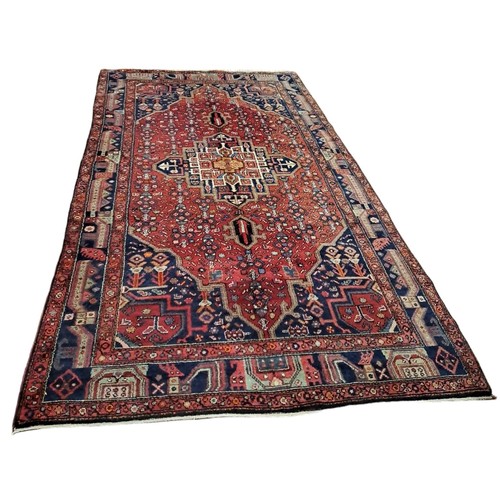 398 - A HAMADAN WOOL RUG the multicoloured ground with central panel filled with stylised flowerheads and ... 