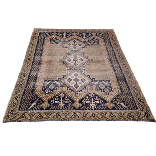 595 - AN ORIENTAL WOOL RUG the light brown ground with central panel with serrated panels filled with hook... 