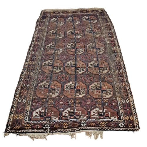 595 - AN ORIENTAL WOOL RUG the light brown ground with central panel with serrated panels filled with hook... 