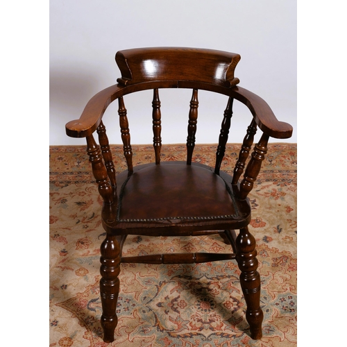 40 - A VINTAGE OAK CAPTAIN'S CHAIR the curved top rail with baluster splats and upholstered seat on bobbi... 