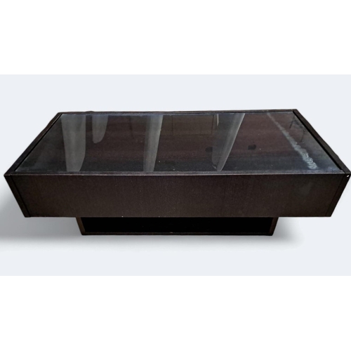 711 - AN EBONISED AND GLAZED COFFEE TABLE of rectangular outline the shaped top with glazed inset above a ... 