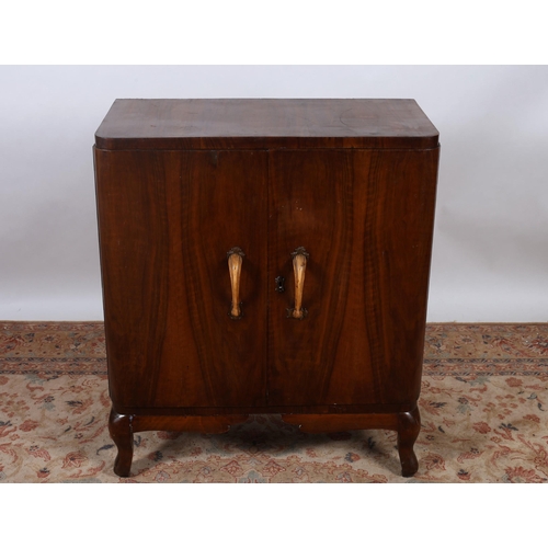 71 - A VINTAGE WALNUT SIDE CABINET of rectangular outline the shaped top above a pair of cupboards contai... 