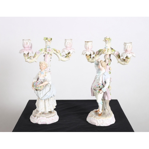 100 - A PAIR OF 19TH CENTURY CONTINENTAL PORCELAIN FLOWER ENCRUSTED TWO BRANCH FIGURAL CANDELABRA each mod... 