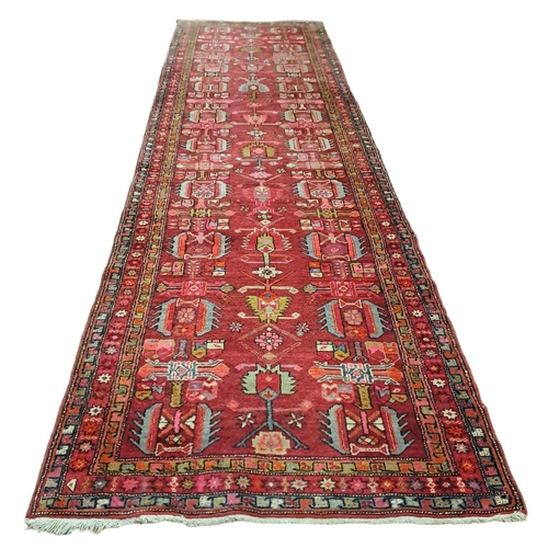 162 - AN ORIENTAL WOOL RUNNER the wine ground with central panel filled with serrated panels, animals, hoo... 