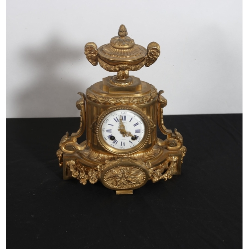 269 - A 19TH CENTURY GILT BRASS CLOCK the oval case surmounted by a neo-classical urn with ram head handle... 