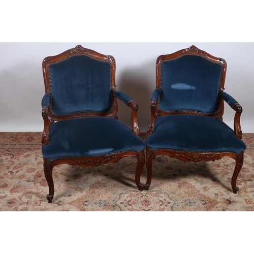 372 - A PAIR OF CONTINENTAL CARVED MAHOGANY AND UPHOLSTERED ARMCHAIRS each with a shaped top rail with uph... 