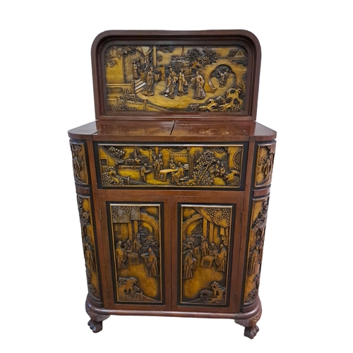 376 - AN ORIENTAL MAHOGANY COCKTAIL CABINET carved overall with figures, pagodas, flowerheads and foliage ... 