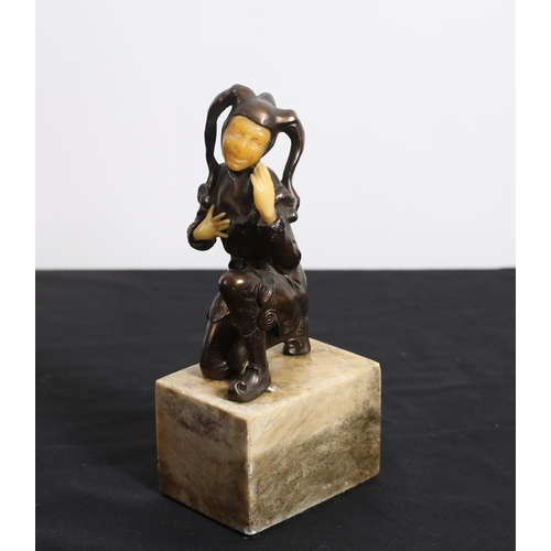 478 - A BRONZED FIGURE modelled as a court jester shown kneeling on a rectangular marble base 
20cm (h)