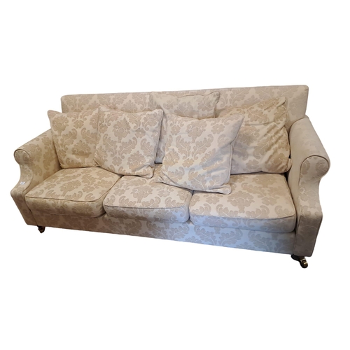 494 - A THREE SEATER SETTEE the rectangular upholstered back and seat with loose cushions and scroll over ... 