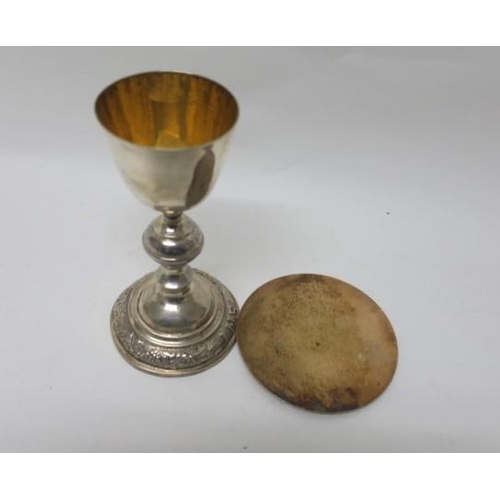 523 - A SILVER AND GILT LINED CHALICE embossed with fruiting vines inscribed 'I.H.S.' together with silver... 