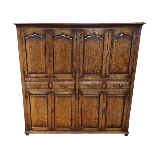 67 - A JACOBEAN DESIGN OAK CUPBOARD the moulded cornice above four blind panel doors above four frieze dr... 