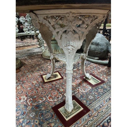 380 - A 19TH CENTURY CAST IRON PATIO TABLE surmounted by a black veined marble top raised on figural mask ... 