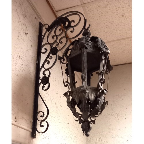 122 - A PAIR OF WROUGHT IRON WALL MOUNTED LANTERNS each of octagonal form with foliate decoration raised o... 