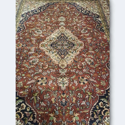 522 - A TABRIZ WOOL RUG the maroon, beige and indigo ground with central panel filled with stylised flower... 