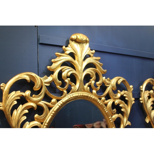 386 - A PAIR OF CONTINENTAL GILTWOOD MIRRORS the oval plate within a pierced C-scroll and foliate frame wi... 