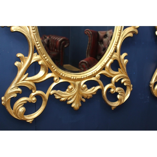 386 - A PAIR OF CONTINENTAL GILTWOOD MIRRORS the oval plate within a pierced C-scroll and foliate frame wi... 