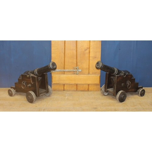 388 - A PAIR OF CAST IRON CANNONS raised on a stepped stained wood carriage with cast iron wheels 
42cm (h... 