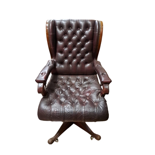 396 - A VINTAGE MAHOGANY AND HIDE UPHOLSTERED WING BACK SWIVEL ARMCHAIR the deep buttoned upholstered back... 