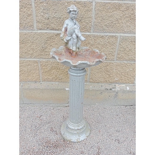 405 - A CAST IRON BIRD BATH the shell shaped bowl surmounted by a putti shown seated above a fluted column... 