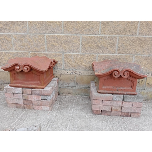 406 - A PAIR OF RED TERRACOTTA PIER CAPS of rectangular scroll form 
28cm (h) x 47cm (w) x 47cm (d)