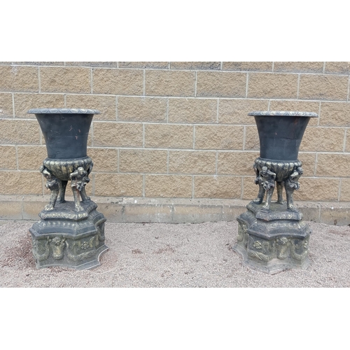 425 - A PAIR OF CAST IRON URNS each of semi lobed campana form raised on figural supports with concave bas... 